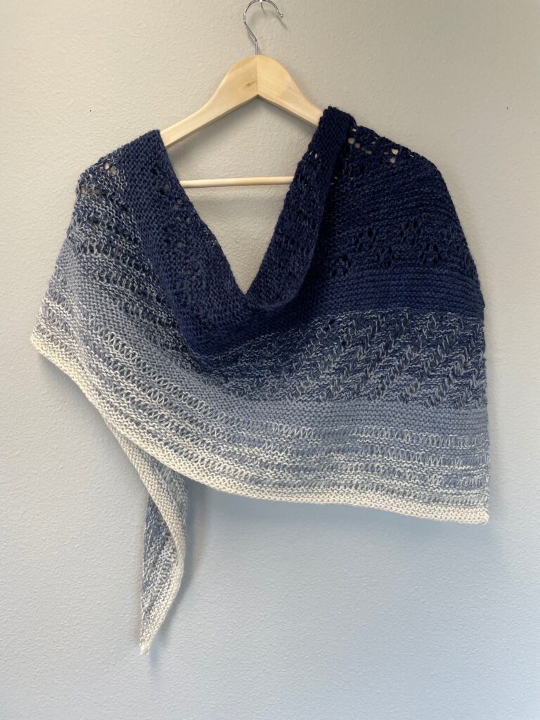 A knitted shawl in shades of blue and white.