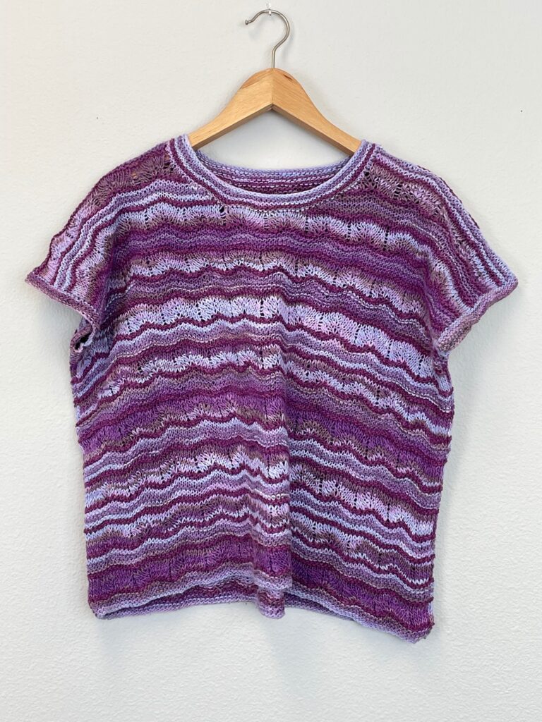 Image shows knitted striped multicolored purple short-sleeved t-shirt.